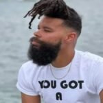 Damon Darling sitting by the water with his signature beard and hairstyle, highlighting Damon Darling Net Worth and career success in 2026.